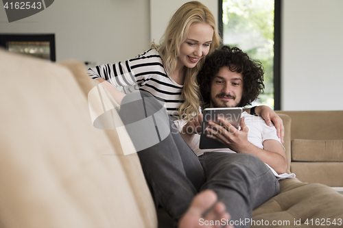 Image of couple relaxing at  home with tablet computers