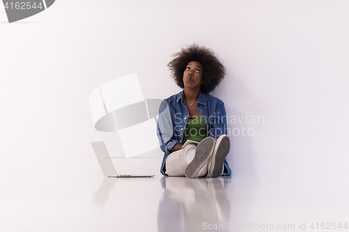 Image of african american woman sitting on floor with laptop