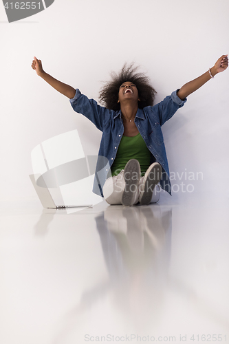 Image of african american woman sitting on floor with laptop