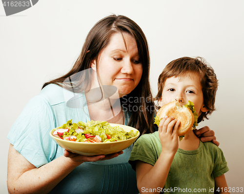 Image of mature woman holding salad and little cute boy with hamburger te