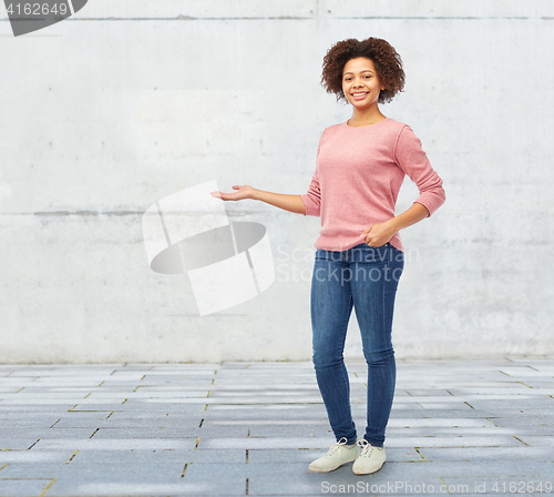 Image of happy african woman holding something imaginary