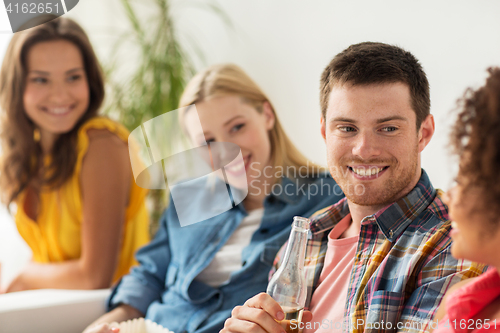 Image of group of happy friends with beer talking at home