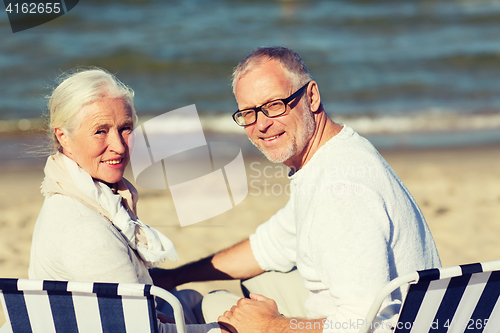 Image of senior couple sitting on chairs at summer beach