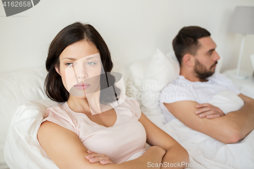 Image of unhappy couple having conflict in bed at home