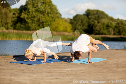 Image of couple making yoga side crane pose outdoors