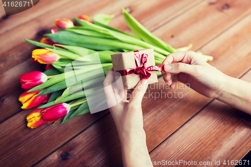 Image of close up of woman with gift box and tulip flowers