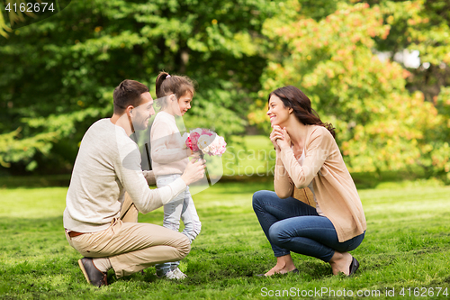 Image of happy family with flowers in summer park
