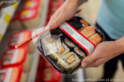 Image of hands with sushi pack at grocery or supermarket
