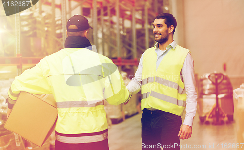 Image of men in safety vests shaking hands at warehouse