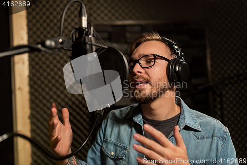 Image of man with headphones singing at recording studio