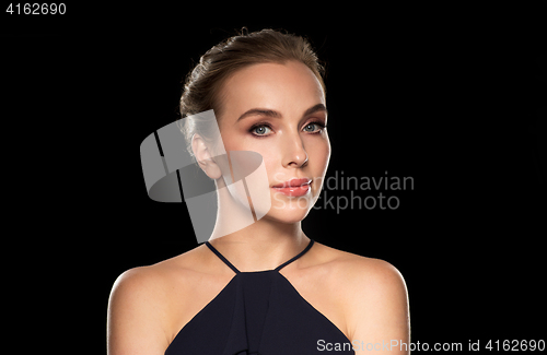 Image of beautiful woman in black over dark background