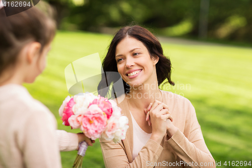 Image of girl giving with flowers to mother in summer park