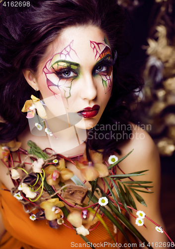 Image of beauty woman with face art and jewelry from flowers orchids clos