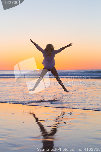 Image of Young beautiful woman jumping in the beach.