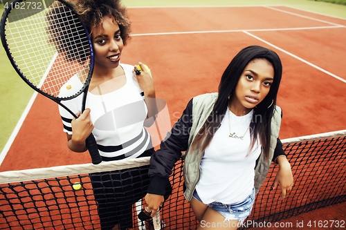 Image of young pretty girlfriends hanging on tennis court, fashion stylis