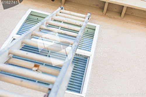 Image of Construction Ladder Leaning Against House