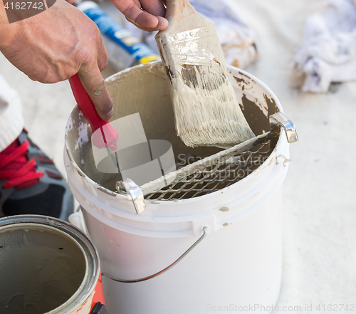 Image of Professional Painter Loading Paint Onto Brush From Bucket