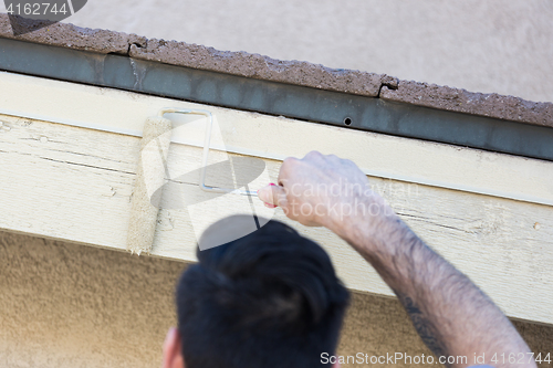 Image of Professional Painter Using Small Roller to Paint House Fascia