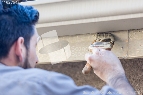 Image of Professional Painter Using Brush to Paint House Fascia Under Rai