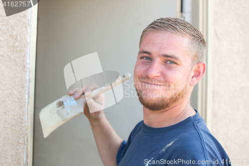 Image of Young Caucasian Man Smiling As He Is Painting House