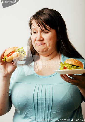 Image of fat white woman having choice between hamburger and salad close 