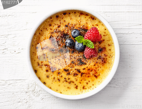 Image of bowl of creme brule on white wooden table