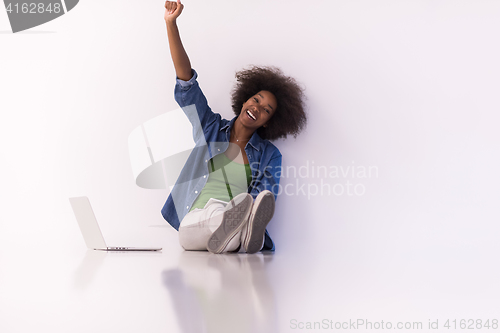 Image of african american woman sitting on floor with laptop