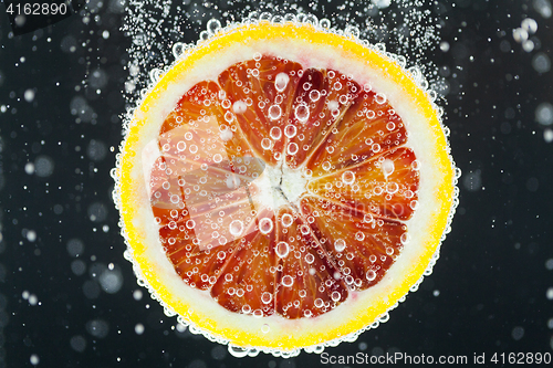 Image of Orange citrus slice falling into water