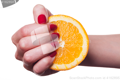 Image of Hand with manicured nails touch an orange on white