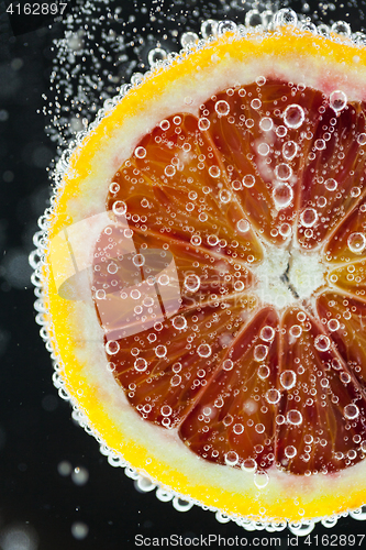 Image of Orange citrus slice falling into water