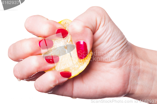 Image of Hand with manicured nails squeeze lemon on white