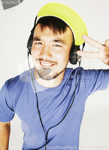 Image of young asian man in hat and headphones listening music on white b