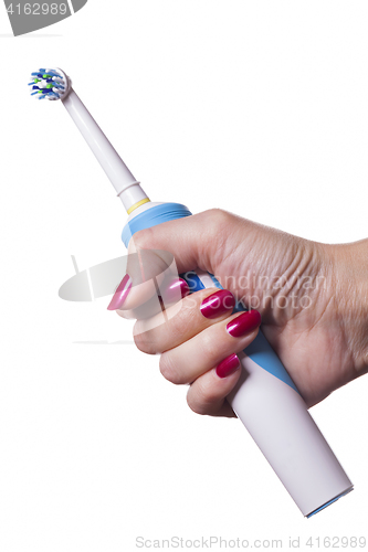 Image of Hand holds electric toothbrush against white