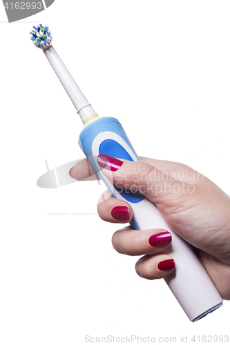 Image of Hand holds electric toothbrush against white