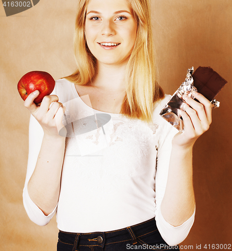 Image of young beauty blond teenage girl eating chocolate smiling, choice