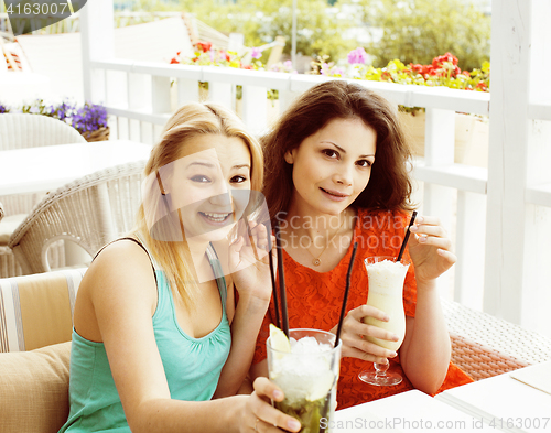 Image of portrait of two pretty modern girl friends in cafe open air inte