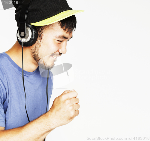 Image of young asian man in hat and headphones listening music on white b