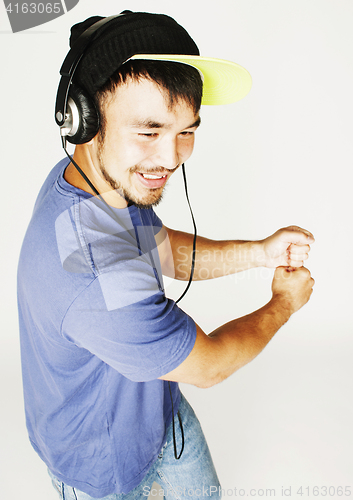 Image of young asian man in hat and headphones listening music on white b