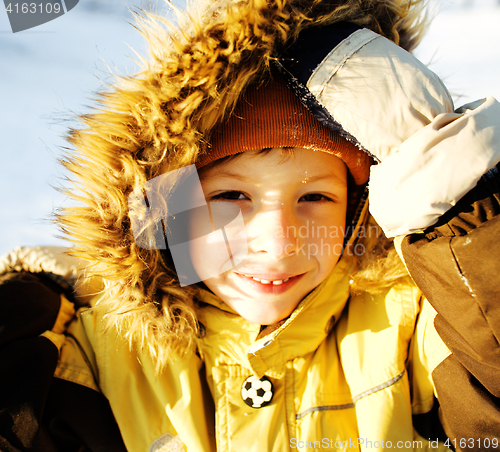 Image of little cute boy in hood with fur on snow outside