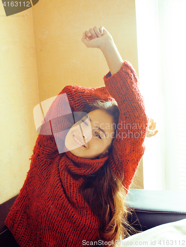 Image of young pretty real woman in red sweater and scarf all over her fa