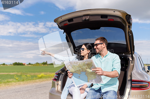 Image of happy man and woman with road map at hatchback car