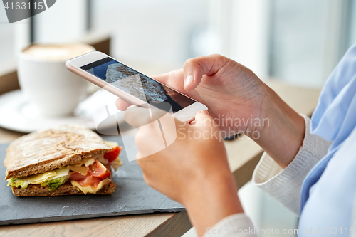 Image of hands with smartphone photographing food