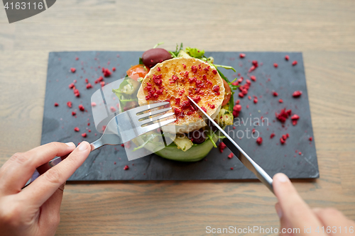 Image of woman eating goat cheese salad at restaurant