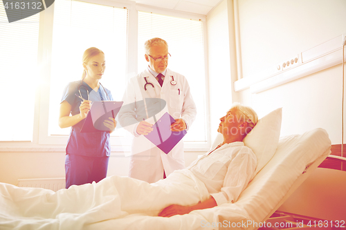 Image of doctor and nurse visiting senior woman at hospital