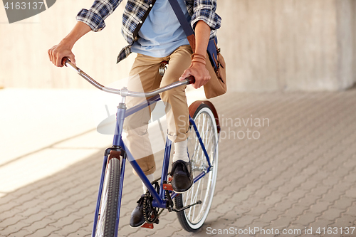 Image of young hipster man with bag riding fixed gear bike