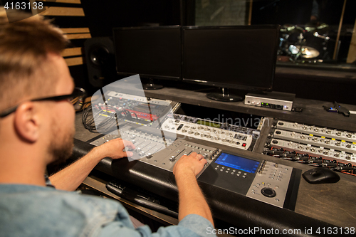 Image of man at mixing console in music recording studio