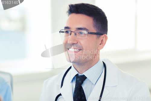 Image of smiling male doctor in white coat and eyeglasses