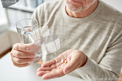 Image of close up of old man hands with pills and water