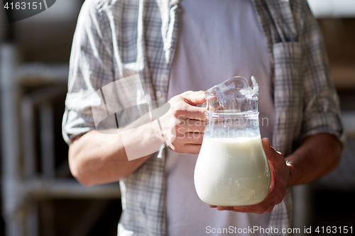 Image of close up of man or farmer with milk on dairy farm