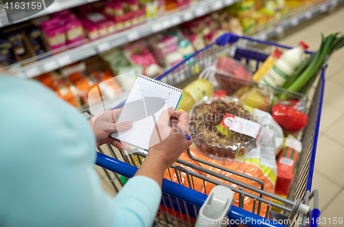 Image of woman with food in shopping cart at supermarket